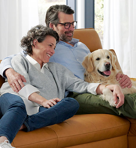 Mann, Frau und Hund auf cognacfarbigem Ledersofa