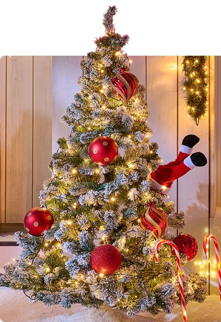 Beleuchteter Weihnachtsbaum mit und im Schnee mit rot-weißen Kugeln, Weihnachtsmann-Beinen, beleuchteten Zuckerstangen