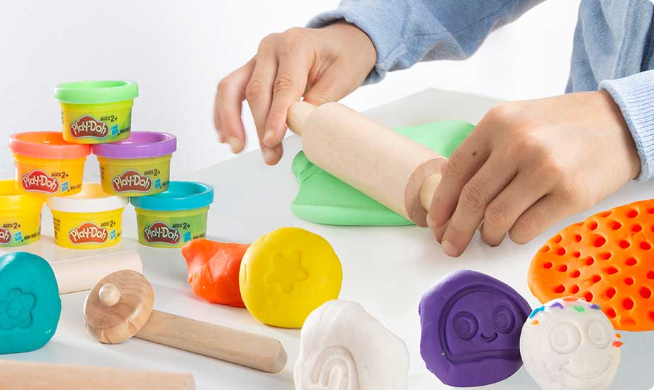 Spielsituation: Zwei Kinderhände spielen mit einem Spielset Play-Doh.