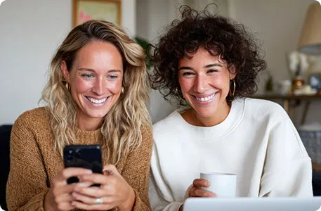 Zwei Frauen sitzen vor einem Laptop.