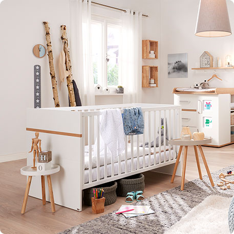 Babyzimmer mit Babybett, Wickelkommode - alle weiß mit Holzakzenten - Kommode mit bunten Bildern - Spielzeug, weitere Möbel