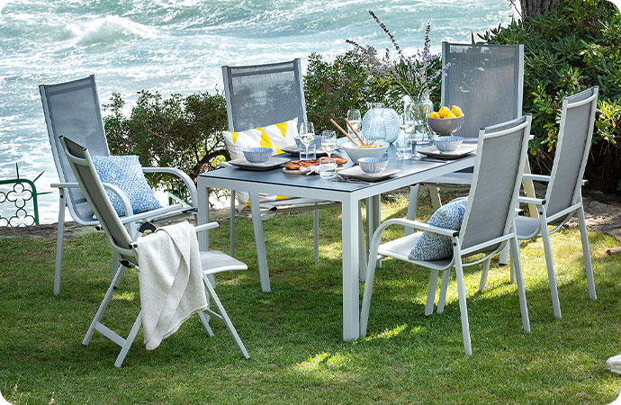 Gartenmöbel aus Aluminium in einem Garten am Meer, bestehend aus Gartentisch mit Glastischplatte und 6 Gartenstühlen