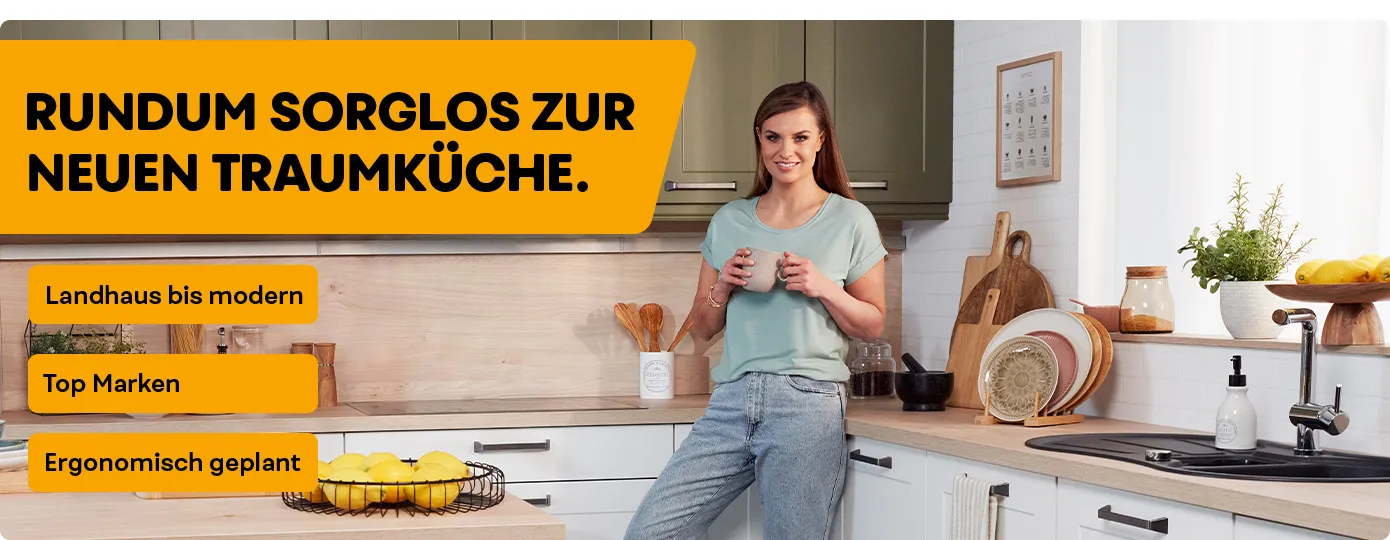 Laura Wontorra steht in einer weißen Küchen, die Arbeitsplatte und Rückwand ist naturfarben, die Oberschränke in einem matten dunklem Grün. Deko.