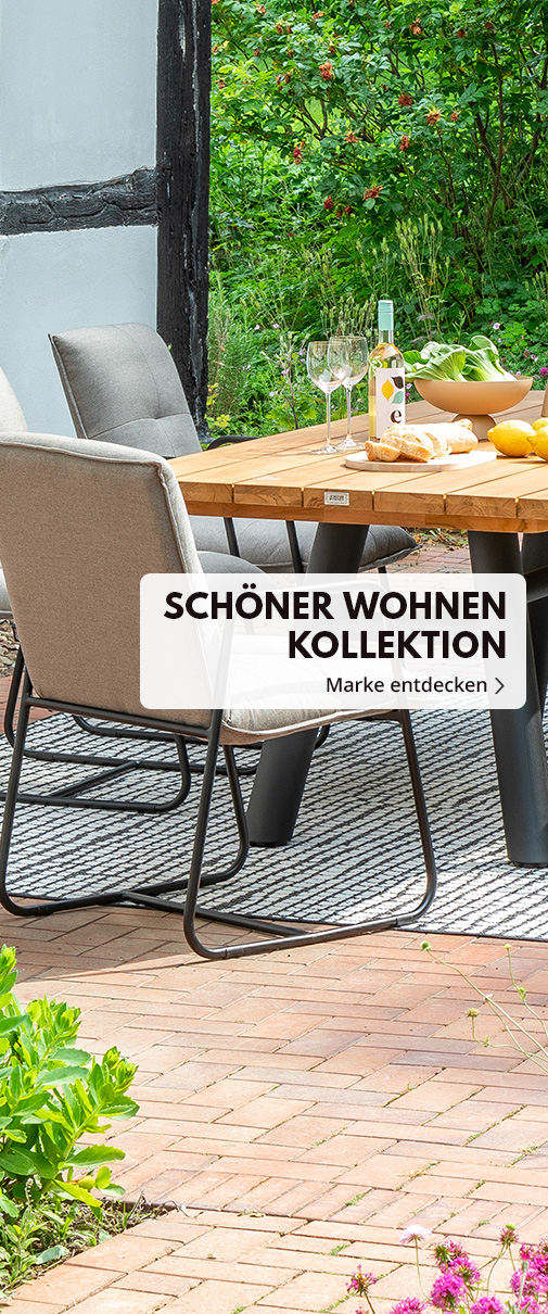 Tischgruppe vor Fachwerkhaus im Garten, Tisch mit Tischplatte in Farbe Natural, Gestell schwarz, Stuhl Sitzkissen Farbe Beige, Gestell schwarz. Text Schöner Wohnen Marke entdecken