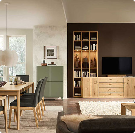 Wohnzimmer mit Holzesstisch und schwarzem Polsterstuhl mit Holzgestell, Wohnwand aus Holz, grünem Highboard