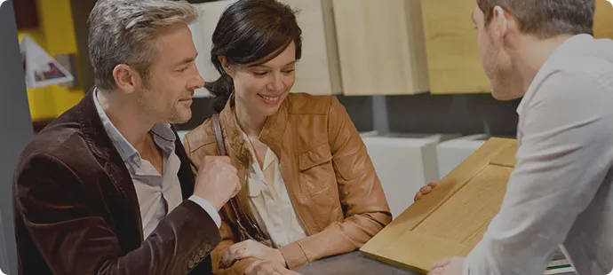 Paar in Beratung. Einrichtungsberatung zeigt Küchenfrontmuster aus Holz.