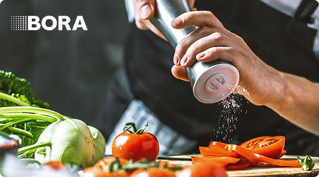 Koch streut Salz auf Tomaten