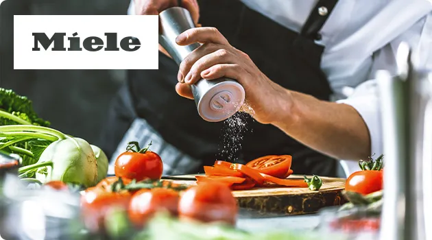 Koch streut Salz über Tomaten