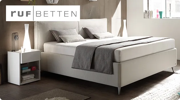 Schlafzimmer mit Boxspringbett in Creme und Nachttisch