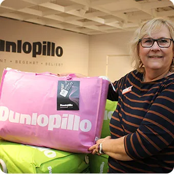 Frau hält ein Paket mit Dunlopillo-Ware in der Hand