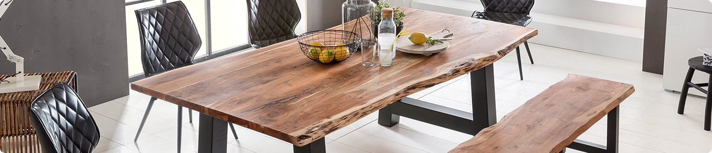 Esstisch mit Tischplatte aus Echtholz und Baumkante an den Längsseiten, A-Gestell aus schwarzem Metall, Bank mit Sitzplatte aus Echtholz und Baumkante an den Längsseiten, schwarze Lederstühle, in einem Esszimmer