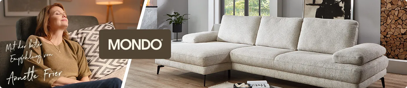 Mondo. Annette Frier sitzt auf Sofa. Text: Mit der besten Empfehlung von Annette Frier. beiges Ecksofa, schwarzer Couchtisch in Wohnzimmer