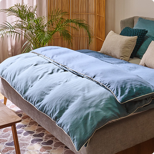 Grauem Bett mit blauer Bettwäsche, beigen und blauen Kissen, in einem Schlafzimmer