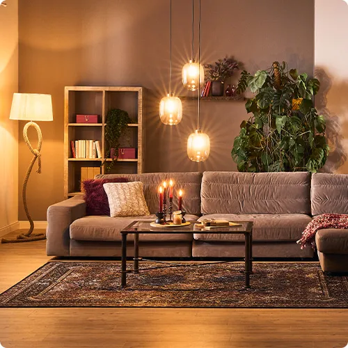 graues Samtsofa mit Kissen und Decke, schwarzer Metallcouchtisch mit Deko, Orientteppich in einem Wohnzimmer