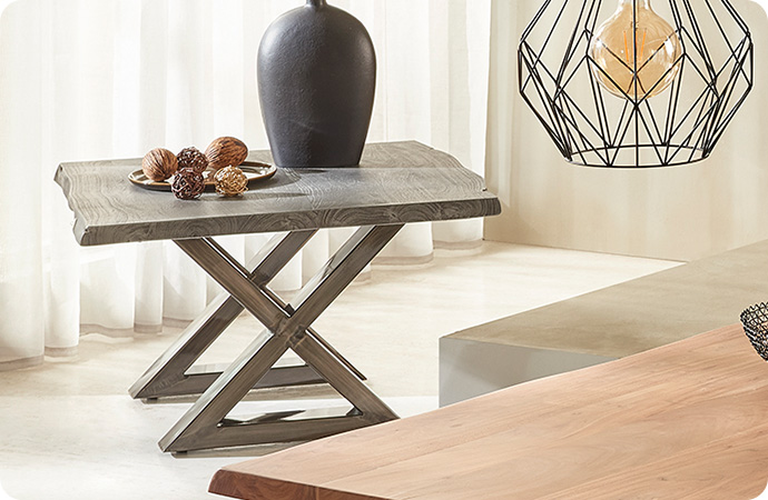 dekorierter Couchtisch aus Echtholz mit X-Gestell aus Metall, anschnittene Holztischplatte und Lampe aus Drahtgeflecht