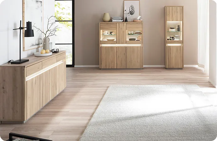 Wohnzimmer mit beleuchteten Holzmöbeln, bestehend aus Sideboard, Highboard und Vitrine. Bild 2: Detail eines offenen beleuchteten Fachs mit Deko.