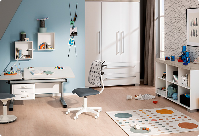 Grau-weißer Kinderschreibtisch und Kinder-Drehstuhl  in Grau und Weiß sowie Hocker in Grau und Weiß in einem Kinderzimmer