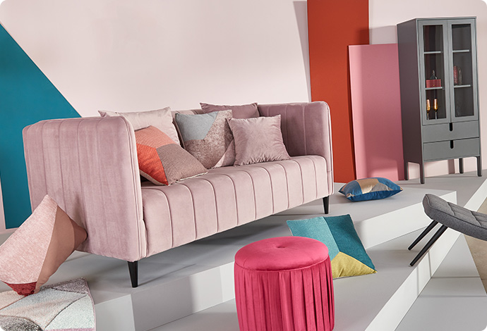 rosa Sofa mit Kissen in Pastelltönen, pinker Hocker, weitere Deko 
