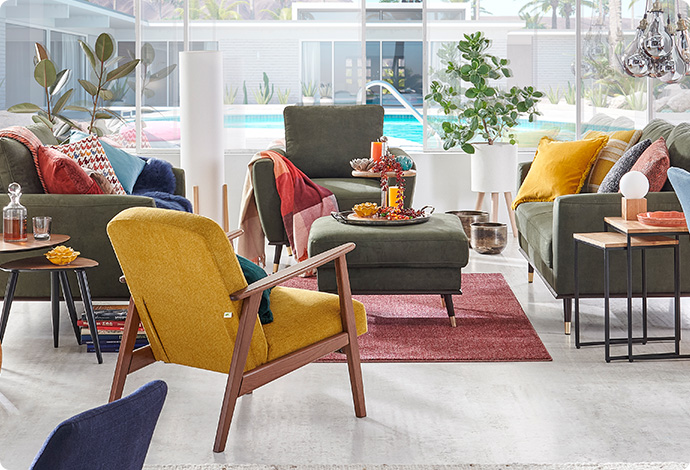 gelber Sessel mit Holzgestell, grüne Polstergruppe, Deko in einem Wohnzimmer 