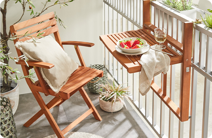 Balkon mit Klappstuhl und Klapptisch, der am Geländer befestigt ist, beide Möbel aus Holz