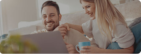 Pärchen auf dem Sofa, das auf einen Laptop schaut