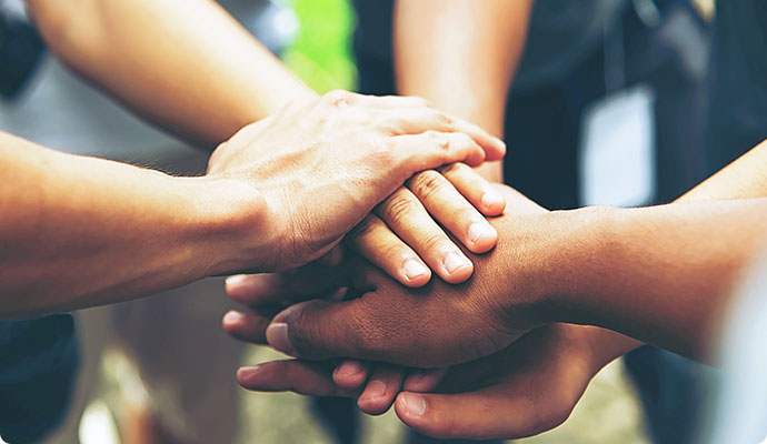 Fünf Personen legen ihre Hände übereinander.