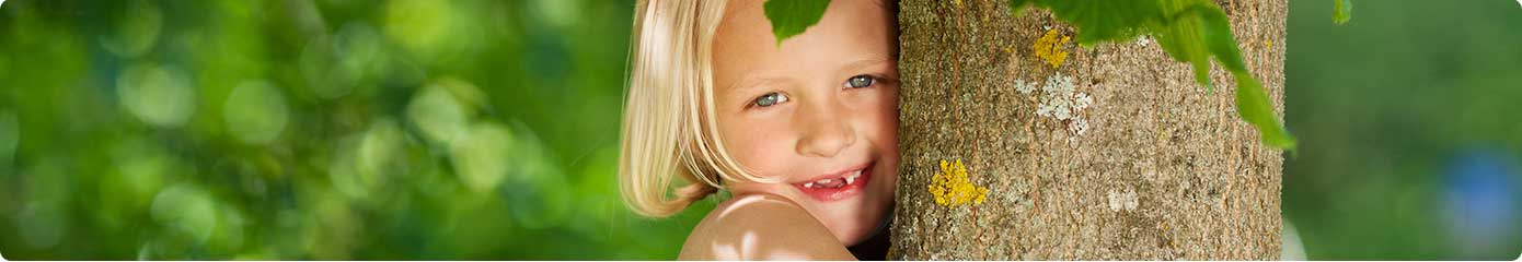 Mädchen umarmt einen Baum im Wald