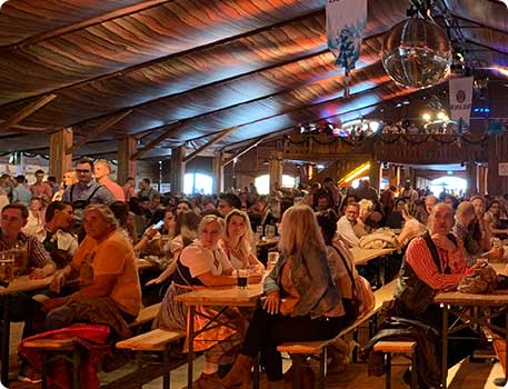 Innenaufnahme Oktoberfestzelt mit Menschen auf Bierbänken an Tischen