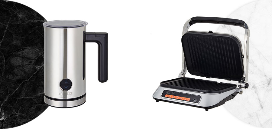 Meisterkoch-gelabelter Milchschäumer vor Halbkreis aus schwarzem Marmor und weißer Fläche sowie offener Kontaktgrill vor Halbkreis aus weißem Marmor und weißer Fläche