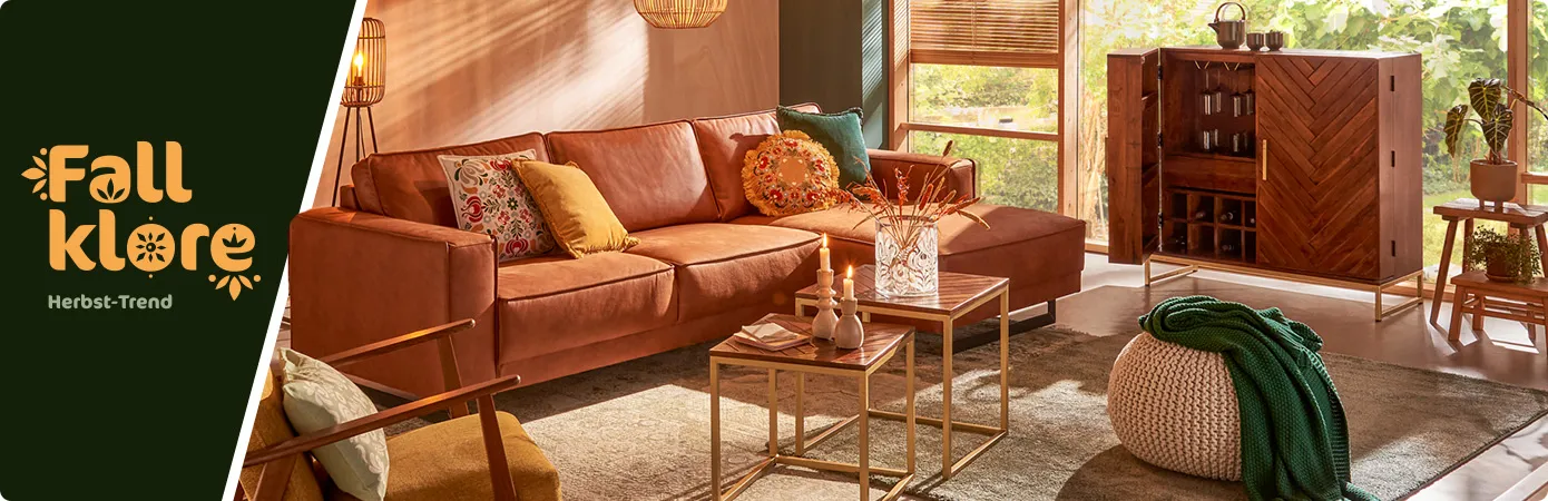 Fallklore Herbsttrend 24. Wohnzimmer mit Holzmöbeln und braunem Leder-Ecksofa und Deko